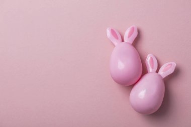 Paskalya yumurtaları pastel pembe bir arka plan üzerinde tavşan kulaklı