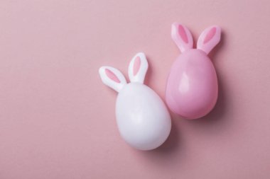 Paskalya yumurtaları pastel pembe bir arka plan üzerinde tavşan kulaklı
