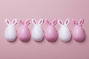 Paskalya yumurtaları pastel pembe bir arka plan üzerinde tavşan kulaklı