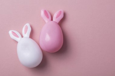 Paskalya yumurtaları pastel pembe bir arka plan üzerinde tavşan kulaklı