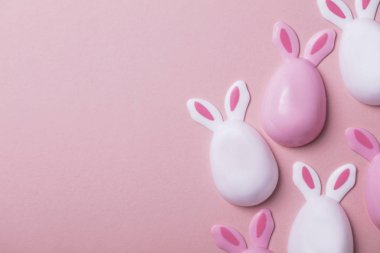 Paskalya yumurtaları pastel pembe bir arka plan üzerinde tavşan kulaklı