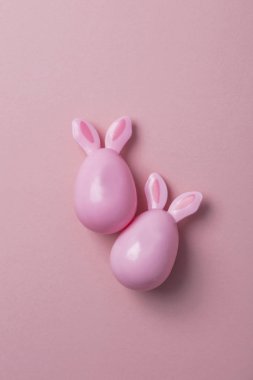 Paskalya yumurtaları pastel pembe bir arka plan üzerinde tavşan kulaklı