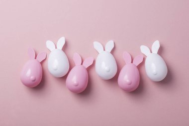 Paskalya yumurtaları pastel pembe bir arka plan üzerinde tavşan kulaklı