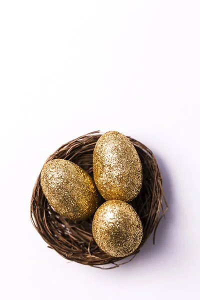Goldene Glitzereier in einem Nest. Osterhintergrund. Finanzierungskonzept — Stockfoto