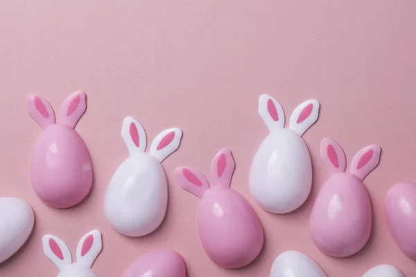 Œufs de Pâques avec des oreilles de lapin sur un fond rose pastel — Photo