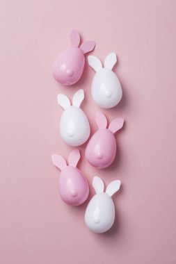 Paskalya yumurtaları pastel pembe bir arka plan üzerinde tavşan kulaklı