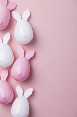 Paskalya yumurtaları pastel pembe bir arka plan üzerinde tavşan kulaklı