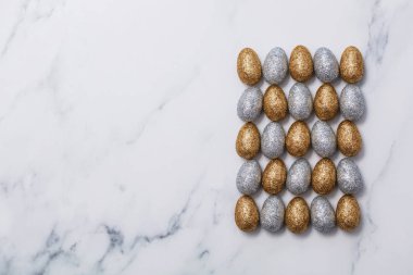 Paskalya yumurtaları mermer bir zemin üzerine altın ve gümüş glitter