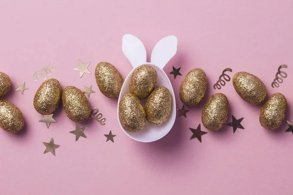 Gold glitter eggs in a white easter bunny egg shape with ears — Stock Photo, Image