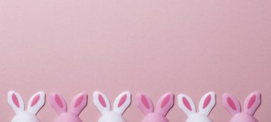 Paskalya yumurtaları pastel pembe bir arka plan üzerinde tavşan kulaklı