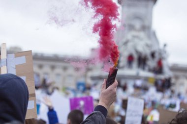 Bir protestocu bir duman bombası siyasi bir gösteride tutar.