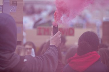 Bir protestocu bir duman bombası siyasi bir gösteride tutar.