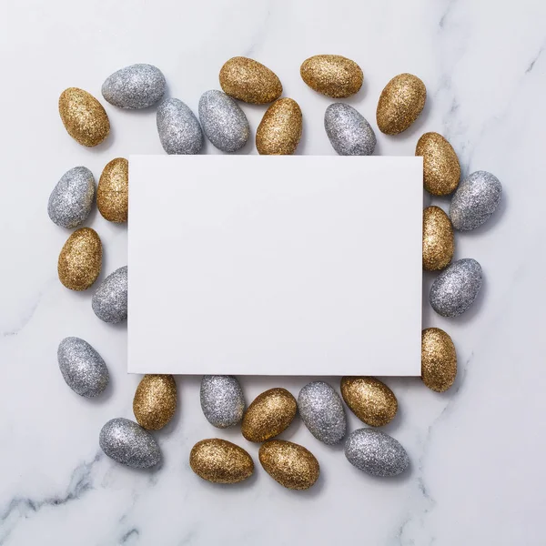 Fundo de Páscoa com um cartão branco em branco e ovos de Páscoa glitter — Fotografia de Stock