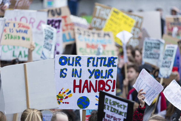 Люди с плакатами протестуют в рамках марша за изменение климата
