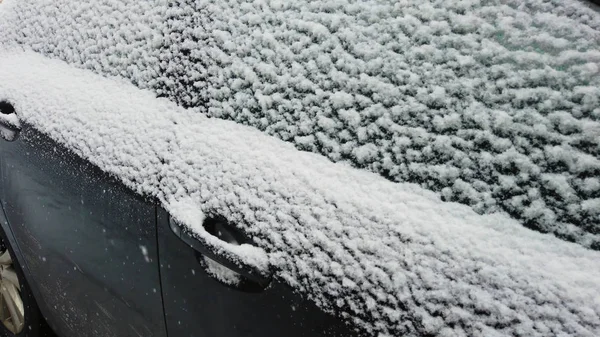 Um carro coberto por uma camada de neve durante uma tempestade de inverno — Fotografia de Stock