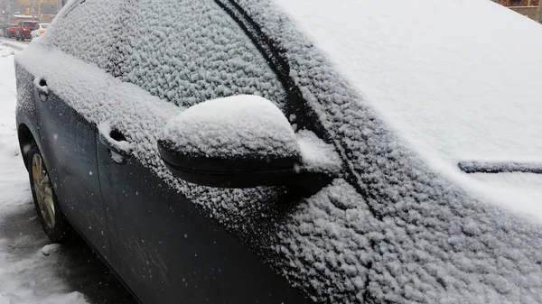 Un coche cubierto de una capa de nieve durante una tormenta de invierno —  Fotos de Stock