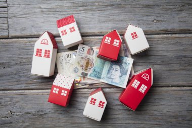 Konut maliyeti. Ingiliz para notları ile kağıt oyuncak ev