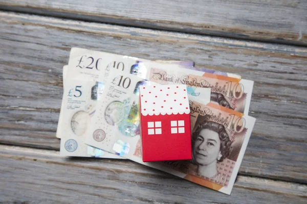 Costo dell'alloggio. Casa giocattolo di carta con banconote inglesi — Foto Stock