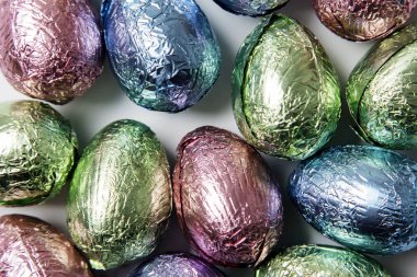 Paskalya yumurtası çikolata mermer arka planda parlak renkli folyo sarılmış davranır