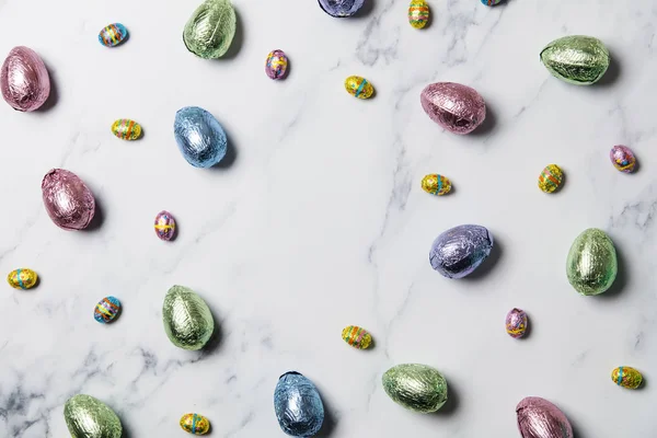 Gâteries au chocolat aux œufs de Pâques enveloppées dans une feuille de couleur brillante sur fond de marbre — Photo