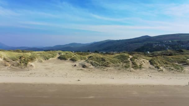 Drone hises high over the beach and sand dunes near the Welsh town of Harlech — Stock Video