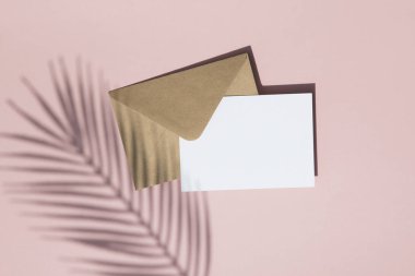 Boş beyaz kart ve kahverengi kağıt zarf üzerinde Yaz palmiye yaprağı gölge kadar mock