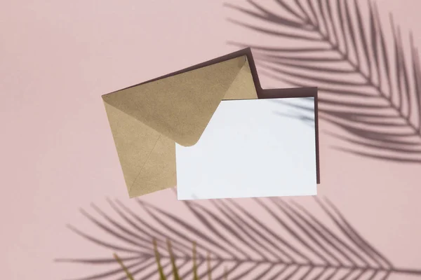 Lato liści palmowych cień na pustej białej karty i brązowy papier koperty makiety — Zdjęcie stockowe