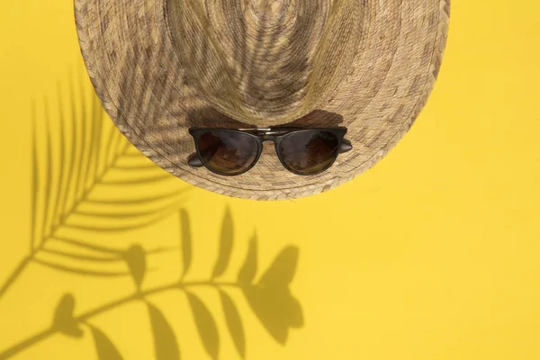 Yaz tatili kompozisyonu. Hasır şapka, güneş gözlüğü ve tropikal palmiye yaprağı gölgesi — Stok fotoğraf
