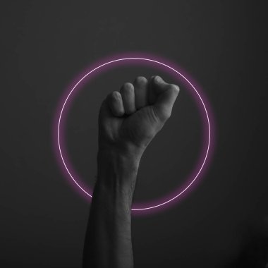 Soyut neon ışık parıltısı ile karanlık bir arka plana karşı yükseltilmiş sıkıştırılmış yumruk