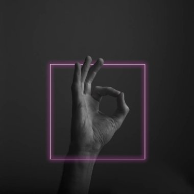 Soyut neon ışık parıltısı ile tamam bir el hareketi kapatın. Tamam el işareti