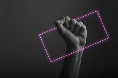 Soyut neon ışık parıltısı ile karanlık bir arka plana karşı yükseltilmiş sıkıştırılmış yumruk