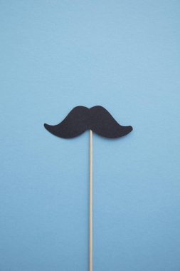 Mavi arka plan üzerinde siyah kağıt bıyık. Babalar günü veya mens sağlık kavramı