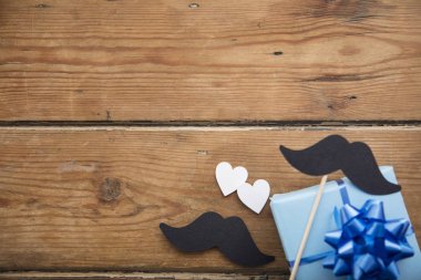 Babalar günü kompozisyonu. Ahşap arka plan üzerinde kalpleri ve bıyık ile Hediye kutusu