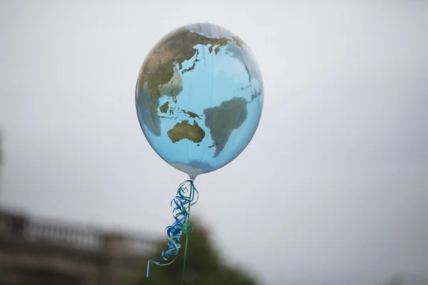 Ein erdförmiger Ballon, der an einer Schnur schwebt. Klima- und Umweltkonzept — Stockfoto