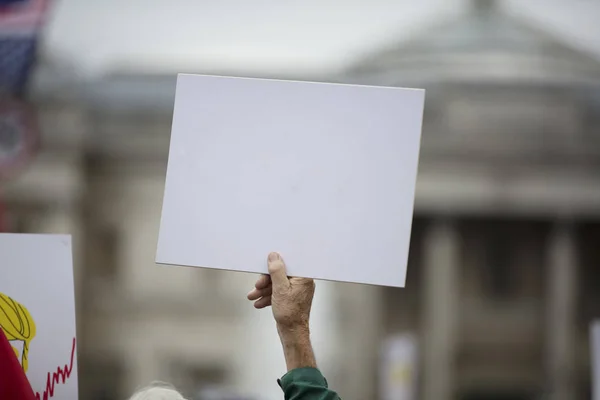 Uma pessoa segurando um banner de protesto em branco em um comício político — Fotografia de Stock