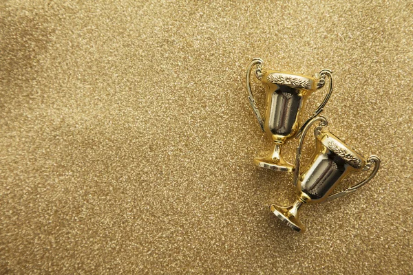 Gold winners achievement trophy on a gold glitter background