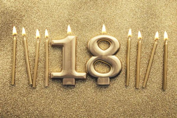 Número 18 vela de celebración de oro sobre un fondo de brillo — Foto de Stock