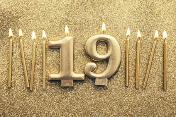 Number 19 gold celebration candle on a glitter background — Stock Photo, Image