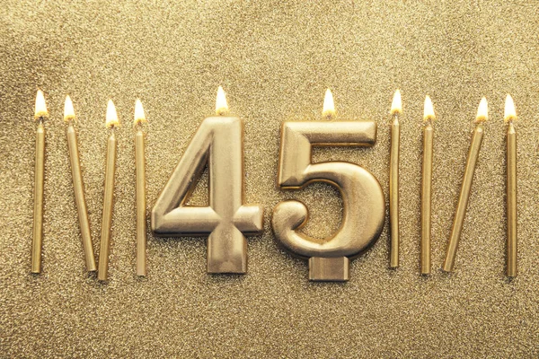 Número 45 vela de celebración de oro sobre un fondo de brillo —  Fotos de Stock