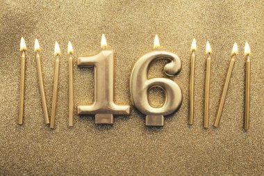 Number 16 gold celebration candle on a glitter background clipart