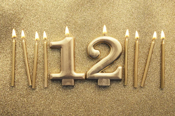 Número 12 vela celebração de ouro em um fundo de brilho — Fotografia de Stock