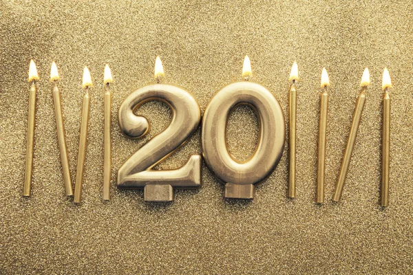 Number 20 gold celebration candle on a glitter background — Stock Photo, Image