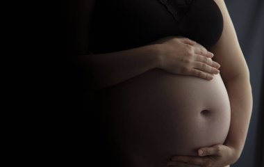 Hamile kadın karanlık bir arka plan karşı bir bebek yumru tutan