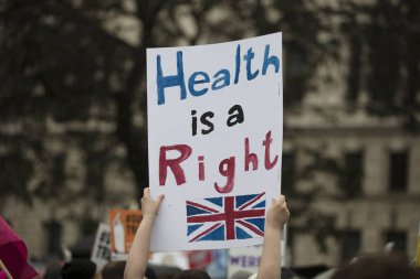 Bir protestocu sağlık ile siyasi bir afiş tutar bir insan hakkı mesajı