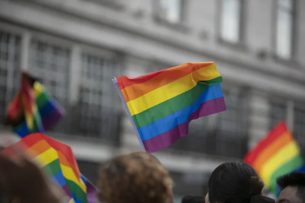 En åskådare vågor en homosexuell regnbåge flagga på en hbt Gay Pride-marsch i London — Stockfoto