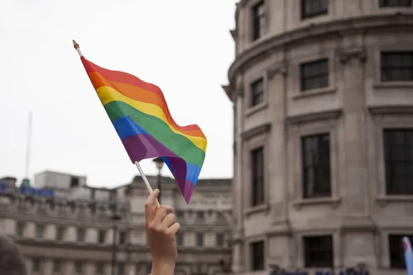 Een persoon met de hand zwaaiende een Gay Pride vlag — Stockfoto