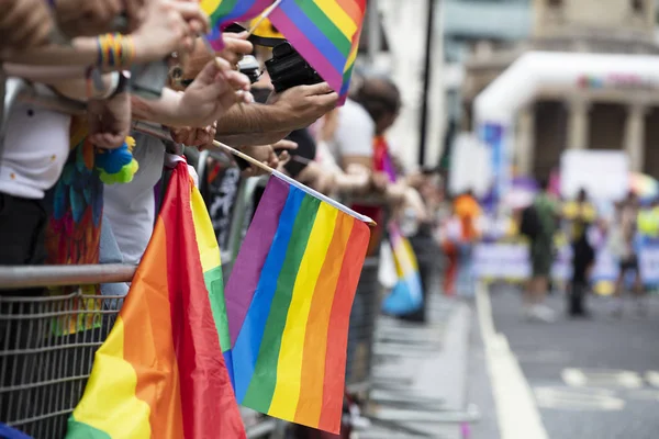 Los espectadores ondean una bandera arco iris gay en un evento de la comunidad LGBT orgullo gay —  Fotos de Stock