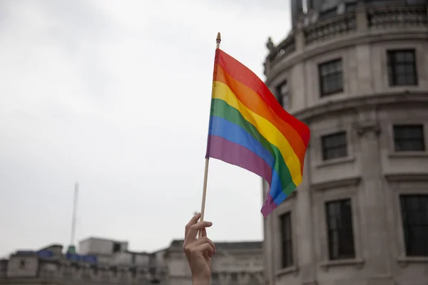 A persons hand waving a gay pride flag