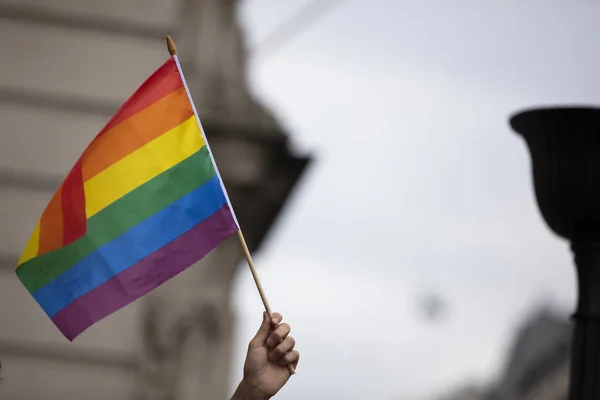 Um espectador acena uma bandeira do arco-íris gay em uma marcha do orgulho gay LGBT em Londres — Fotografia de Stock