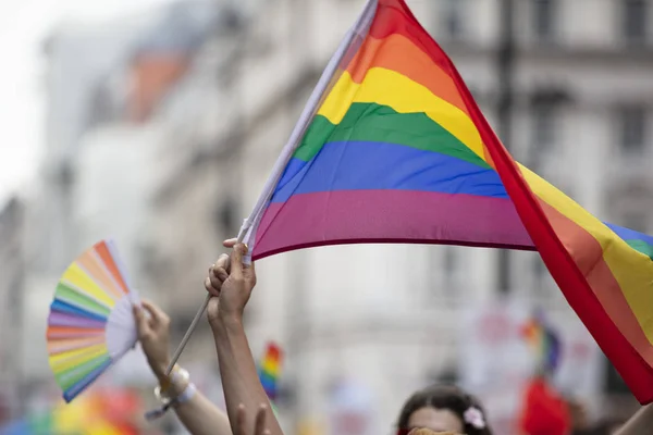 Eine lgbtq Regenbogenfahne, die bei einem Gay Pride Marsch hoch in der Luft geschwenkt wird — Stockfoto